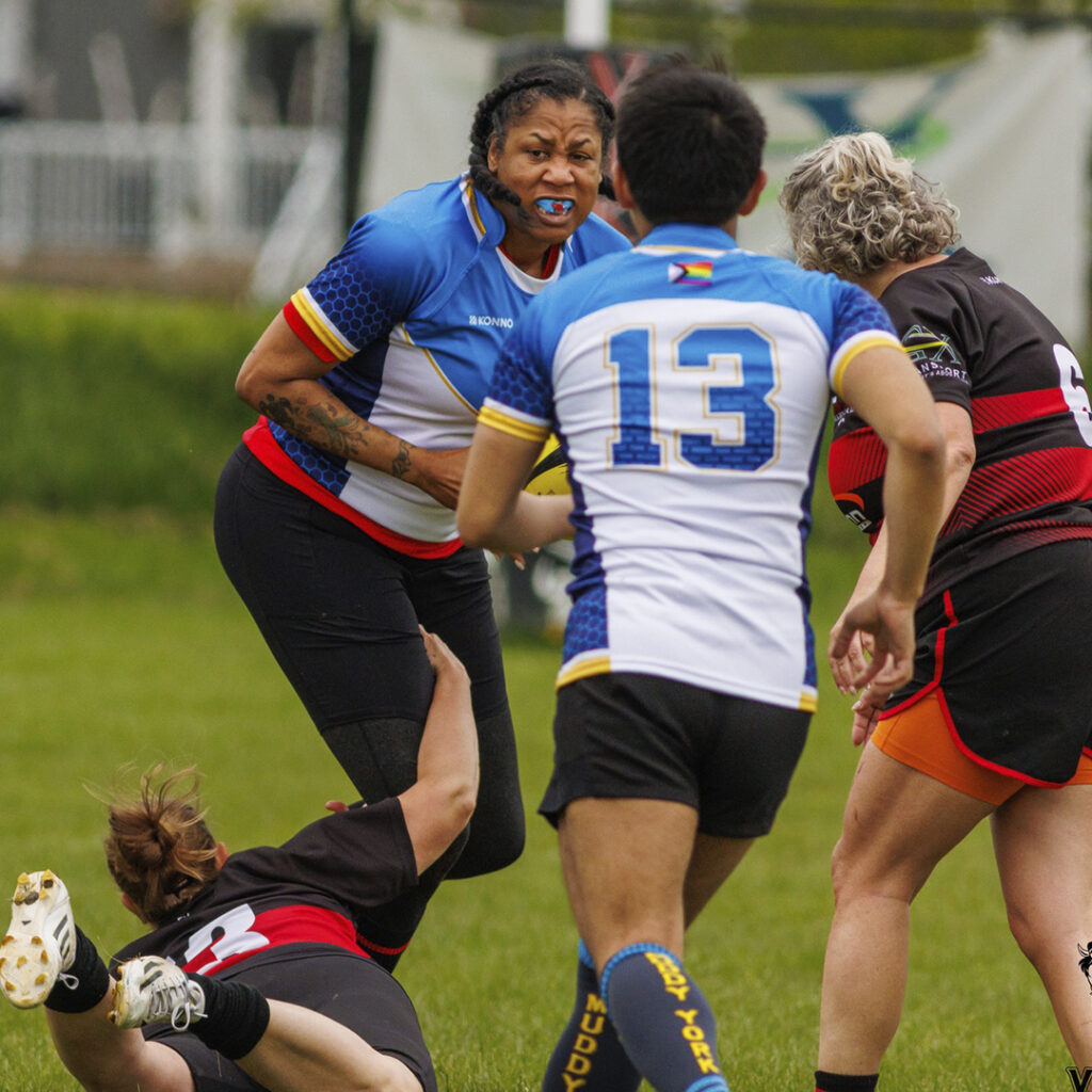 A Muddy York player running through a tackle with the ball in hand.